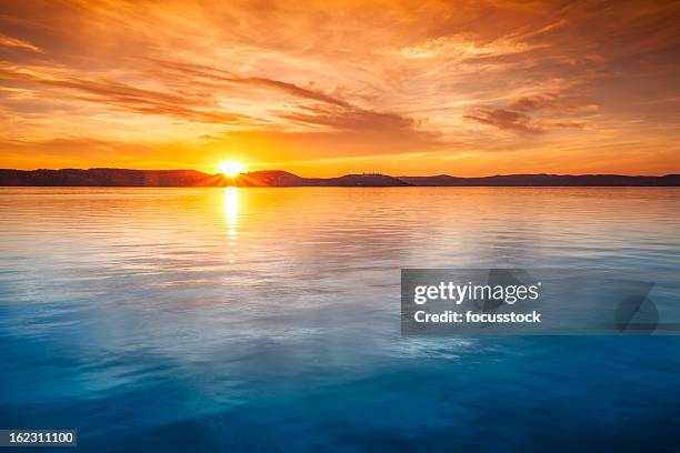 sunset over water - golden clouds stockfoto's en -beelden