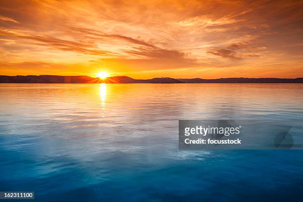 sunset over water - sunset stock pictures, royalty-free photos & images