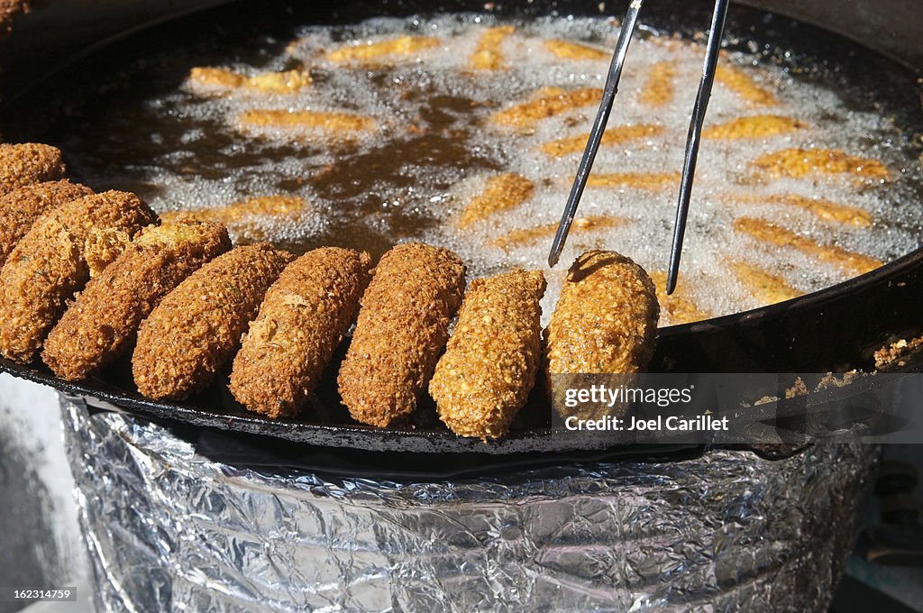 Placing falafel on side of frying pan in Ramallah, Palestine