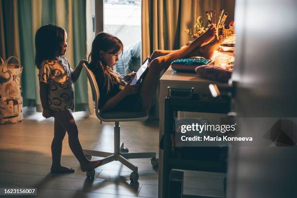sisters share digital tablet phone in children's room at home. - famiglia multimediale foto e immagini stock