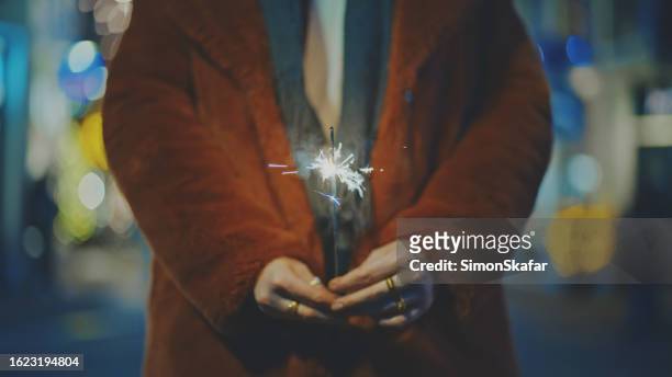 woman in long winter coat holding sparkler in city during christmas - amsterdam winter stock pictures, royalty-free photos & images