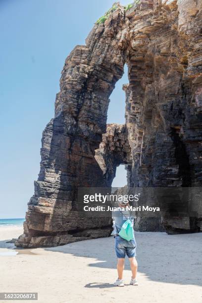 tourist exploring and contemplating "la playa de las catedrales" in ribadeo, province of lugo. - provincia de lugo ストックフォトと画像