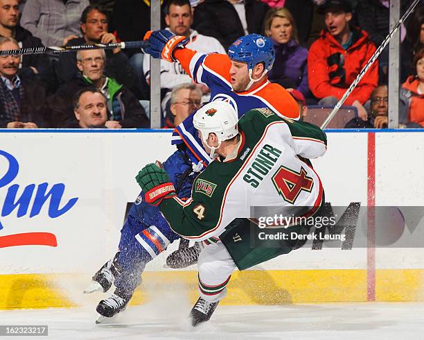 Clayton Stoner of the Minnesota Wild knocks Ben Eager of the Edmonton Oilers off his feet during an NHL game at Rexall Place on February 21, 2013 in...