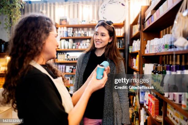 negoziante che assiste la cliente donna che acquista prodotti cosmetici - fitoterapia foto e immagini stock