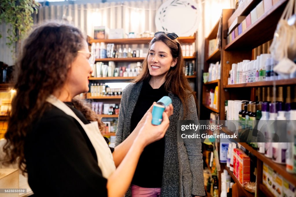 Shopkeeper assisting woman customer buying cosmetic products