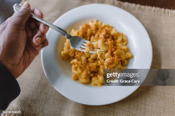 woman eats macaroni and cheese - macaroni and cheese stock pictures, royalty-free photos & images