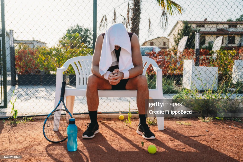 A tennis player is resting during a match