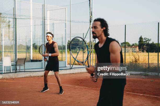 deux joueurs de tennis se concentrent sur le match lors d’un match double - double sportif photos et images de collection