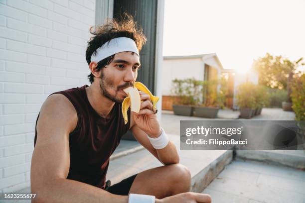 un jugador de tenis está comiendo un plátano durante un descanso - atuendo de tenis fotografías e imágenes de stock