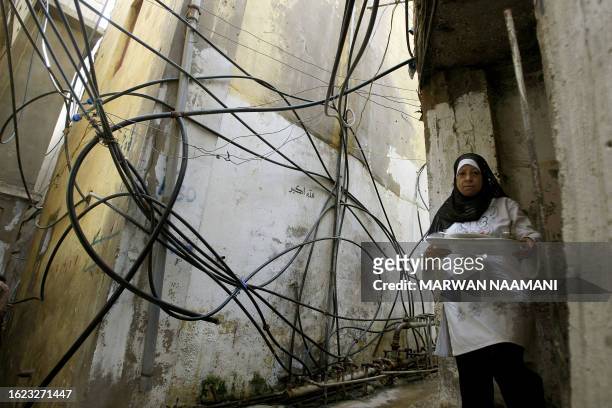 Palestinian refugee walks out from her home in a cramped alley next to a tangled web of waterpipes in the refugee camp of Burj al-Barajneh in Beirut,...