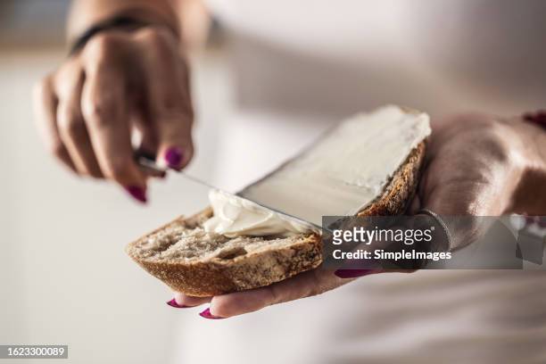 a woman makes delicious bread, spreads cream cheese with a cutlery knife - close up. - making sandwich stock pictures, royalty-free photos & images