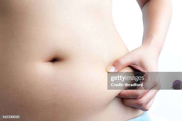 mujer asiática pellizcar grasa en el vientre con la mano izquierda - barrigón fotografías e imágenes de stock