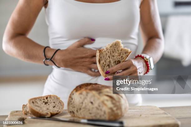a young celiac woman suffers from abdominal pain after eating fresh bread. - glutenfrei stock-fotos und bilder
