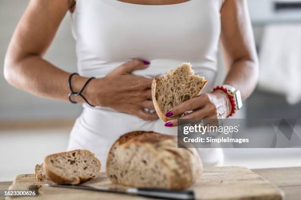 a young celiac woman suffers from abdominal pain after eating fresh bread. - celiac disease stock pictures, royalty-free photos & images