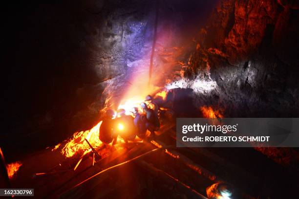 In this photograph taken on January 29 miners keep warm by a fire inside a deep mine shaft as they wait for a water pump to suck water from the...