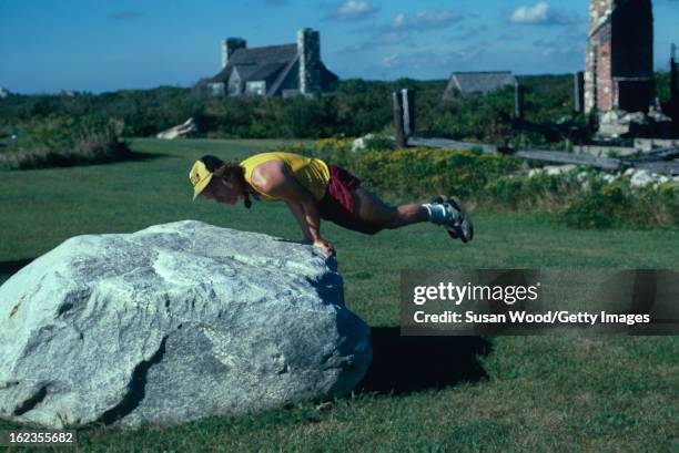 American talk show host and writer Dick Cavett does push-ups on a large rock in the Hamptons, Long Island, New York, September 1984.