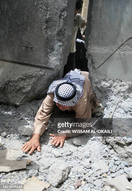 An Iraqi man crawls through a gap in the concrete wall built by the US army spliting in two the restive Sadr City district of eastern Baghdad on May...