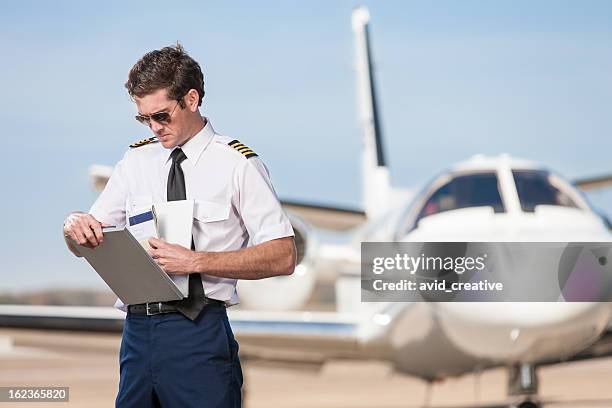 pilot reviewing log book near corporate jet - project charter stockfoto's en -beelden