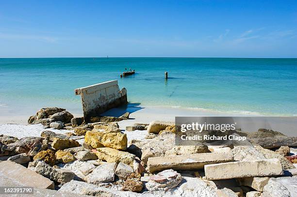 Beach scene showing concrete rubble and the remains of a pier and the beautiful turquoise waters of the Gulf of Mexico in the Sarasota, FL area.