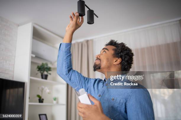 young man is changing a light bulb - changing lightbulb stock pictures, royalty-free photos & images