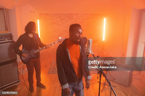 adult black male lead singer and adult male caucasian guitarist recording in a cosy music studio - lead singer stock pictures, royalty-free photos & images