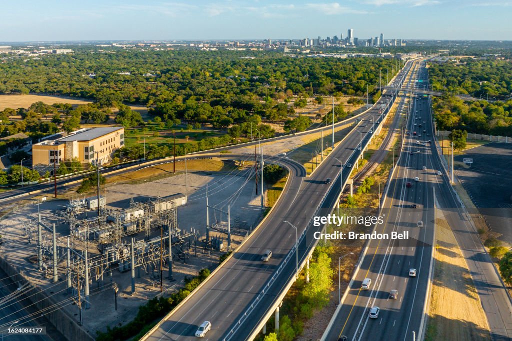 An aerial view of a power plant next to a freeway overpass on