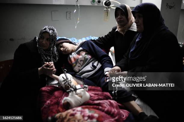 Relatives comfort Palestinian girl, Amira al-Kerm, who was wounded by Israeli tank fire, as she rests after a surgical operation at Al-Shifa hospital...