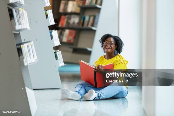 teen girl with down syndrome reading book in library - jeans stock pictures, royalty-free photos & images