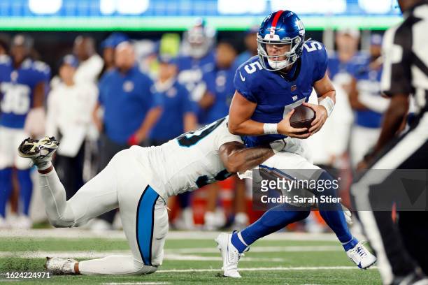 Tommy DeVito of the New York Giants is tackled by Amare Barno of the Carolina Panthers during the second half of a preseason game against the New...