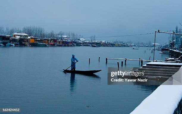 Kashmiri man rows his boat on the waters of Dal lake after a snowfall on February 23, 2013 in Srinagar, Indian Administered Kashmir, India. Several...