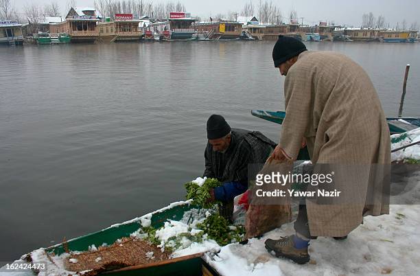 Kashmiri men buy and sell vegetables on the bank of Dal lake after a snowfall on February 23, 2013 in Srinagar, Indian Administered Kashmir, India....