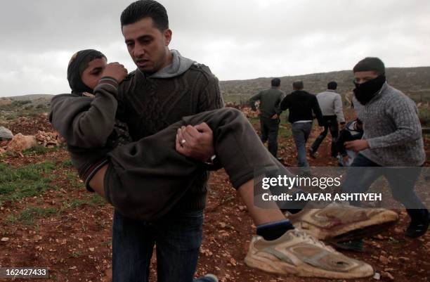 Palestinians aid a wounded proterstor following clashes with Israeli settlers in the West Bank village of Qusra near Nablus on February 23, 2013....