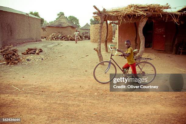 Young boy pushes a bike in a remote Mali village about 2 hours outside Bamako.