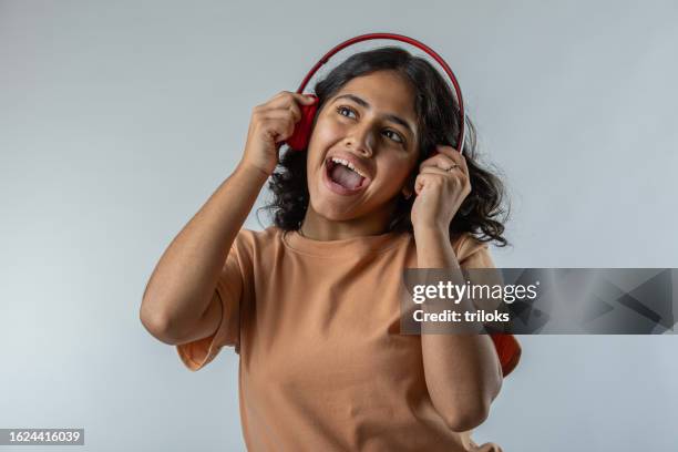 teenage girl screaming and listening music on white background - 15 year old model stock pictures, royalty-free photos & images