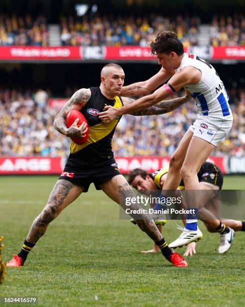 Dustin Martin of the Tigers breaks a tackle attempt from Curtis Taylor of the Kangaroos during the round 23 AFL match between Richmond Tigers and...