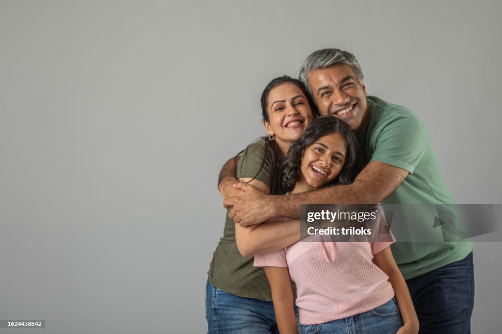 Loving parents embracing daughter over white background