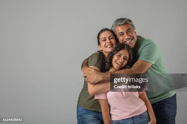 loving parents embracing daughter over white background - indian family portrait stock pictures, royalty-free photos & images