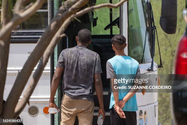 Migrants who have crossed into the US from Mexico in Eagle Pass, Texas, wait to enter a bus which will take them to a processing facility on August...