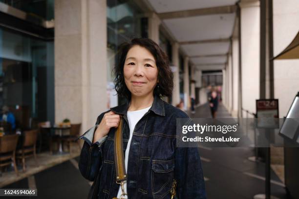 smiling asian woman walking in an arcade - east asian ethnicity stock pictures, royalty-free photos & images