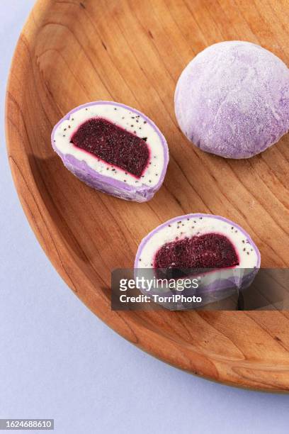 traditional daifuku mochi with lavander flavor and bluberry filling on wooden tray. cut in half dessert on purple background - bluberry imagens e fotografias de stock