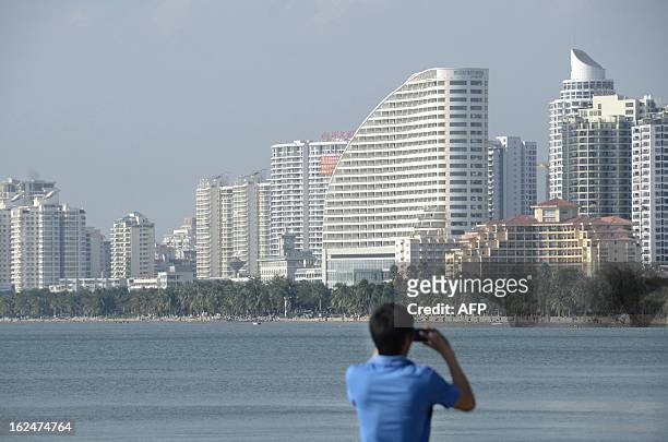 China-economy-property-Hainan,FEATURE by Tom Hancock This picture taken on January 19, 2013 shows a Chinese man taking photos of buildings at the...