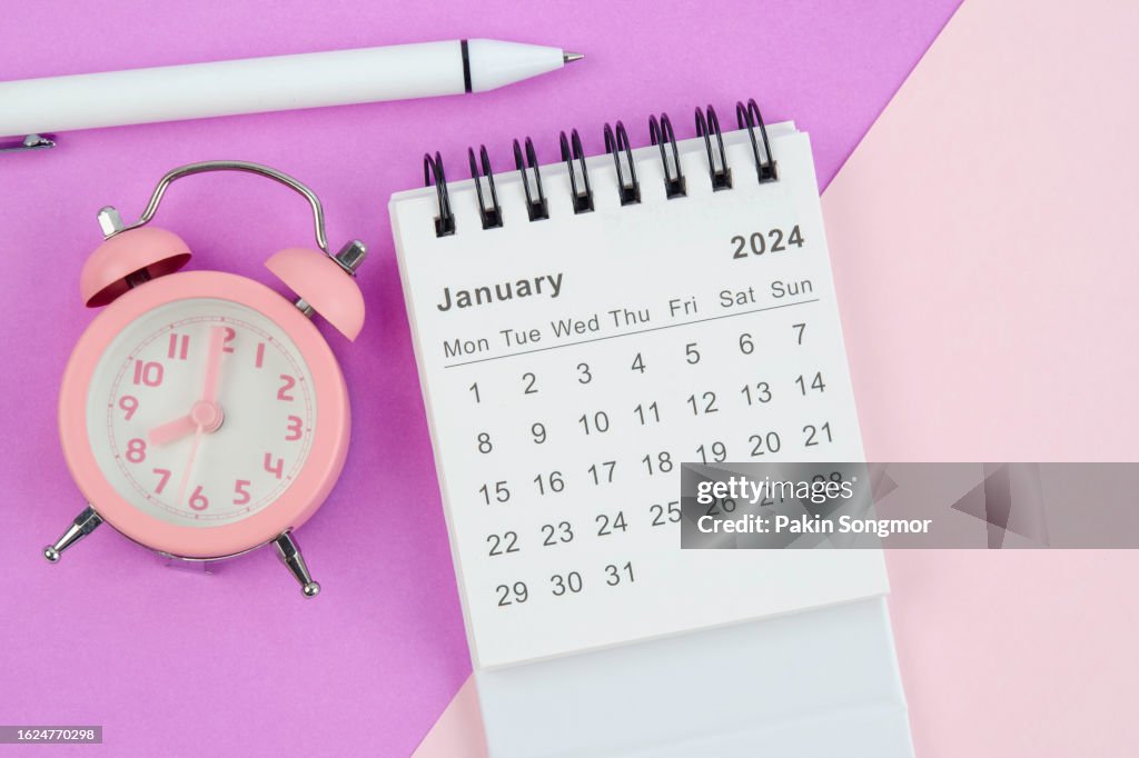 Calendar Desk 2024: January is the month for the organizer to plan and deadline with white pen and alarm clock against a two-tone background.