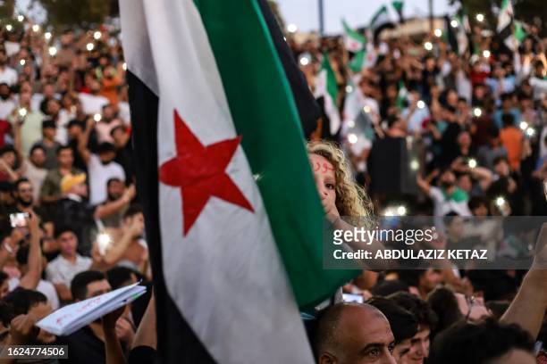 Young girl raises the Syrian opposition flag, during a demonstration in the rebel-held northwestern city of Idlib on August 25 in support of...