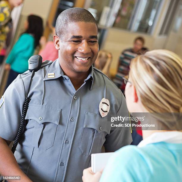 friendly police officer talking with school teacher after safety demonstration - bewaker stockfoto's en -beelden