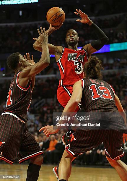 Dwyane Wade of the Miami Heat passes over Jimmy Butler and Joakim Noah of the Chicago Bulls at the United Center on February 21, 2013 in Chicago,...