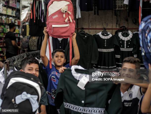 Palestinian children help their father to sell bags and school uniforms during the preparation for the new academic year in the market in Gaza city.