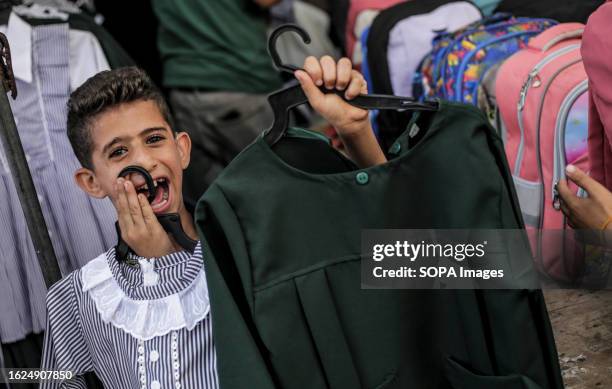 Palestinian child seen with a school uniform during the preparation for the new academic year in the market in Gaza city.
