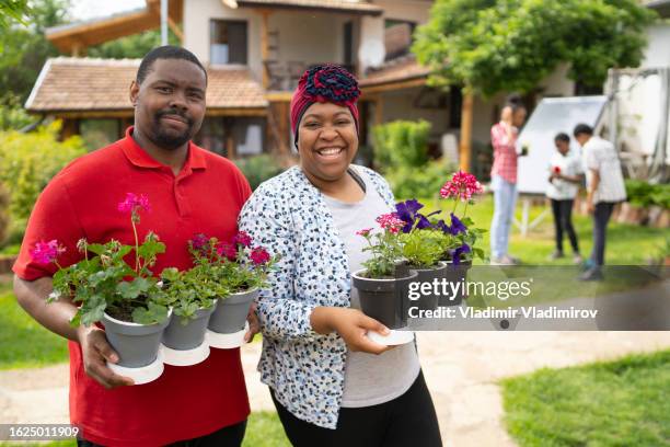 standing in a garden holding plant pots - jamaicaanse etniciteit stockfoto's en -beelden