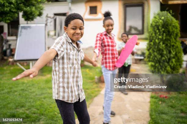 with arms stretched out three children stand side by side in a line - jamaicansk stock pictures, royalty-free photos & images