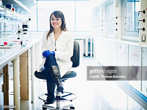 young scientist seated in research laboratory - lunette de protection photos et images de collection